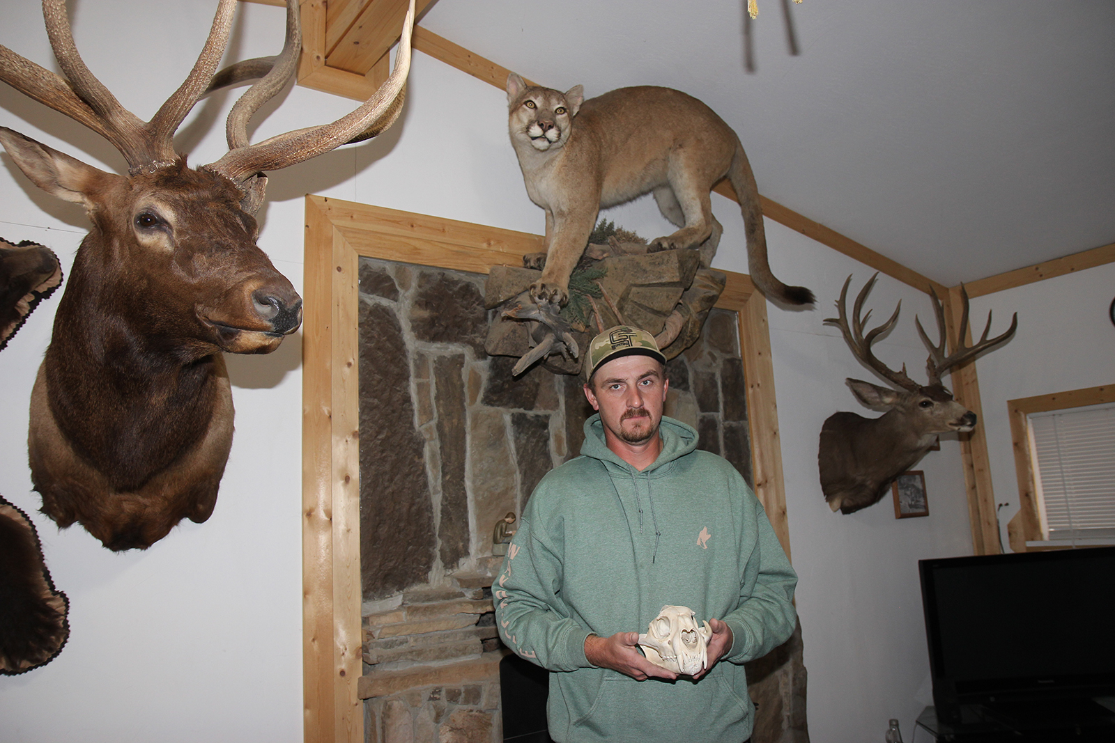 Man with Mountain Lion Skull surrounded by taxidermied animals