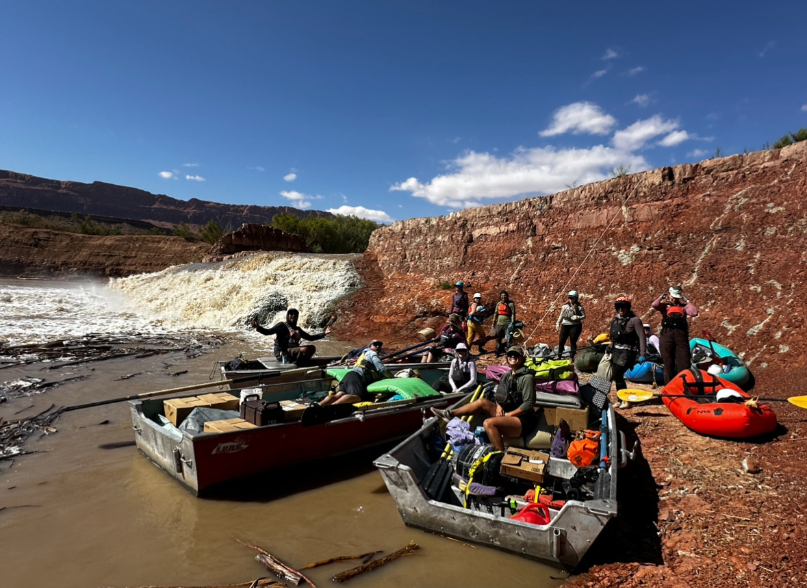 Rafters in boats pose for a photo at the bottom of a raging waterfall.